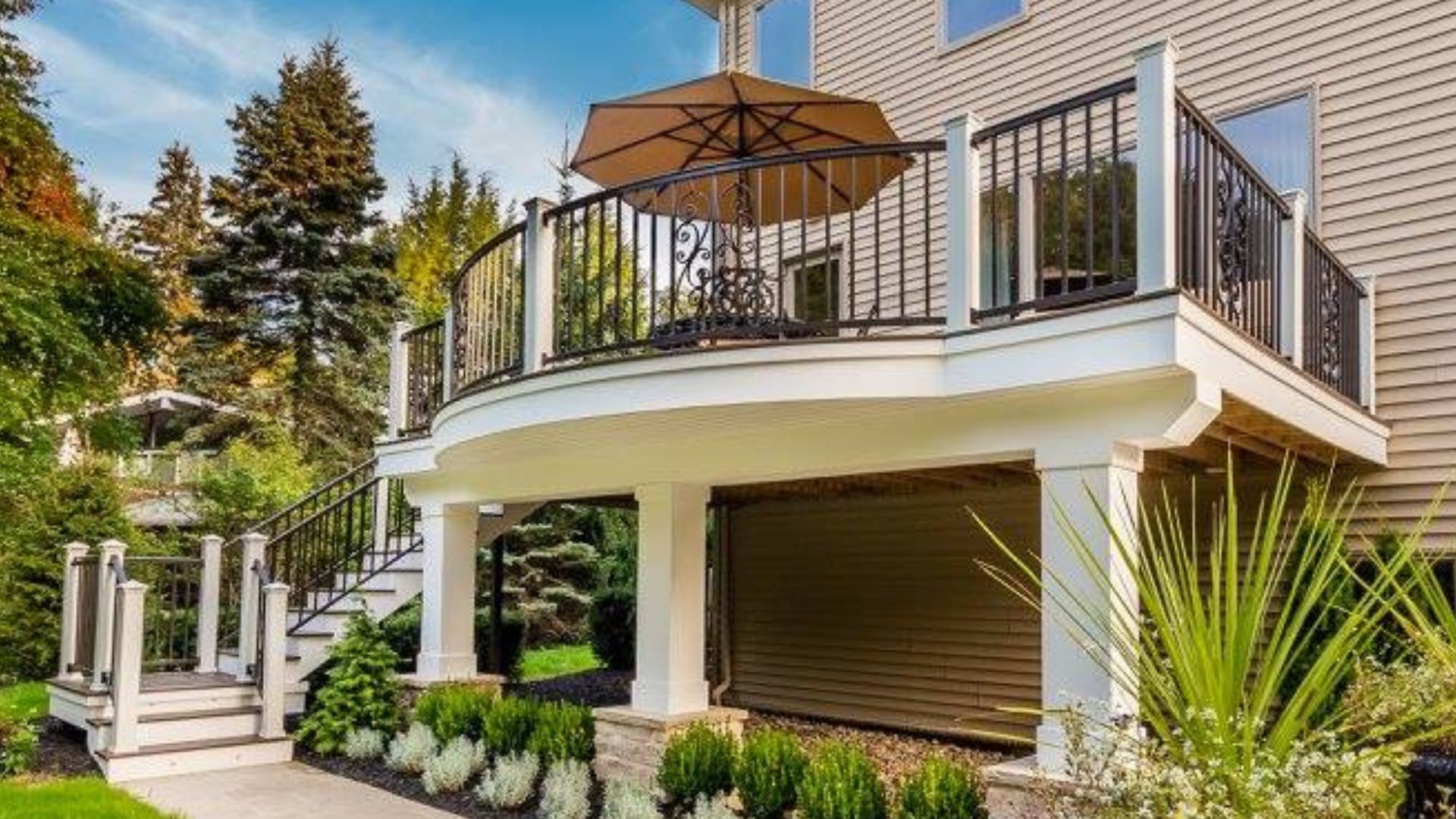 Elevated Round Deck With Black Wrought Iron Railing And Umbrella